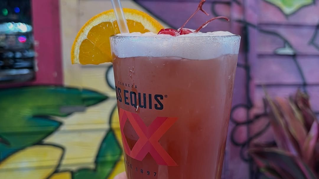 A cold drink in front of the Purple Parrot mural