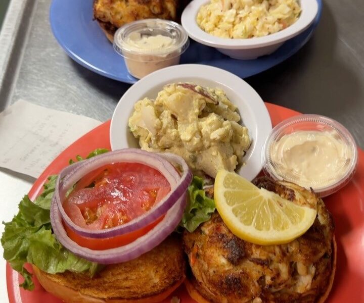 Crab cake sandwich with lettuce, tomato, red onion, tartar and potato salad